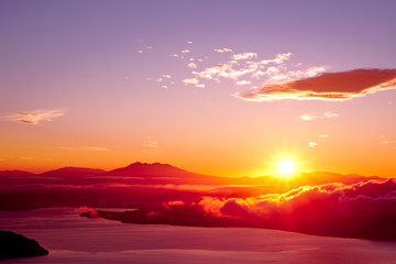 Obraz premium 夜明けの空に力強く輝く太陽。津別峠、北海道。Abstract of sunrise and sunset. The sun is shining in the sky,clouds flowing low,lake surface seen in thin light.Scenic view from high place. Tsubetsu-pass,hokkaido,japan.