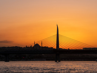 sunset setting behind a silhouetted ataturk bridge in istanbul