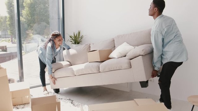 African-American man and woman are moving a sofa. The couple are replacing the furniture in a new apartment. The concept of relocation.