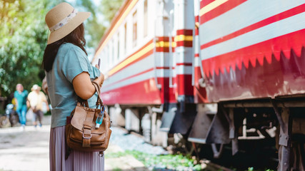 Mini portable alcohol gel bottle to kill Corona Virus(Covid-19) hang on leather shoulder bag of woman at railway staion. New normal lifestyle. Health care concept. Selective focus on alcohol gel