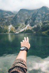 man hand showing beautiful lake in mountains