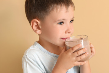 Little boy with tasty chocolate milk on color background