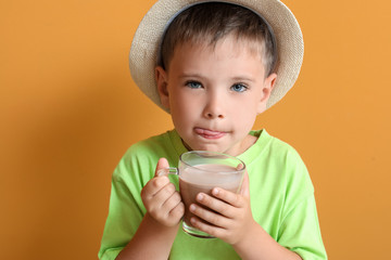 Little boy with tasty chocolate milk on color background