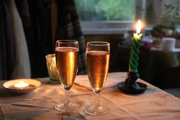 Two glasses with champagne and a candle in the background