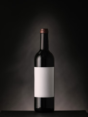 Bottle of wine with blank label on dark background. Mockup for design