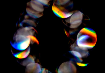 Naklejka premium Lens flare, Bokeh lights. Reflections from glass, diamond, crystal. Defocused shining colorful rainbow light leaks, rays on black background