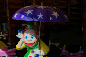Obraz na płótnie Canvas Toy bright clown under a blue umbrella.