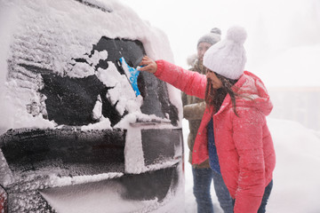 Man cleaning snow from car outdoors on winter day