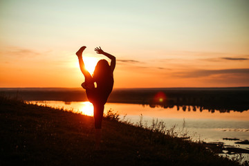 Yoga practice and meditation in nature in sunrise. Woman practicing near big river Kama.