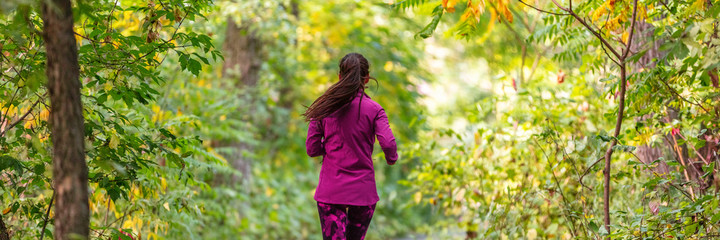 Autumn trail run outdoor sports woman running in forest banner. Panoramic crop of runner athlete training cardio outside in nature park.