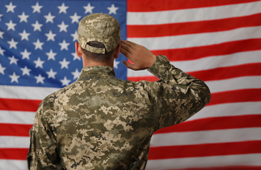 Male soldier in uniform against USA flag, back view