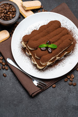 Classic tiramisu dessert and savoiardi cookies on ceramic plate on concrete background
