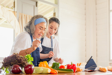 Senior asian mother and middle aged daughter cooking together at kitchen