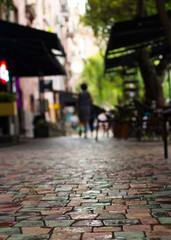 Wet paving stone in the morning after rain and walking woman silhouette