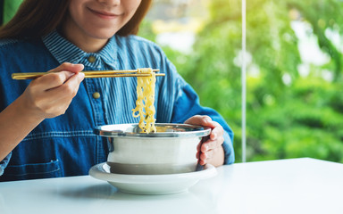 Closeup image of a beautiful woman eating asian style instant noodle at home