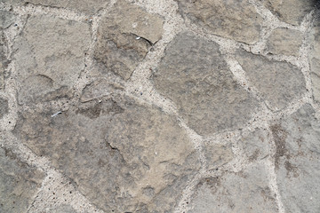 Stone pavement. Texture of stone paved ground. Large jagged stone blocks on a pedestrian sidewalk or road. Ancient masonry. Great for background and design.