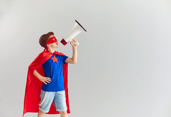 Smiling boy playing role of superhero at home with speaker in hand, copy space © Studio Romantic
