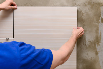 Master tiler lays the tiles on the wall