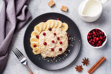 Oatmeal with milk with banana cranberries and sesame seeds. A Cup of coffee, healthy Breakfast Concept.
