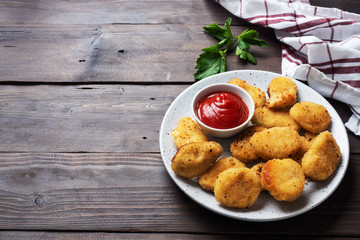 Fried chicken nuggets with tomato ketchup sauce. Wooden background. Copy space.