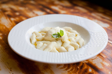 Lazy dumplings - vareniki of cottage cheese on a white plate, close up on wooden background
