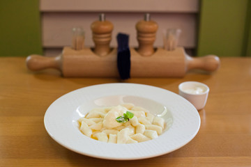 Lazy dumplings - vareniki of cottage cheese on a white plate, served with sour cream sauce, in russian cafe
