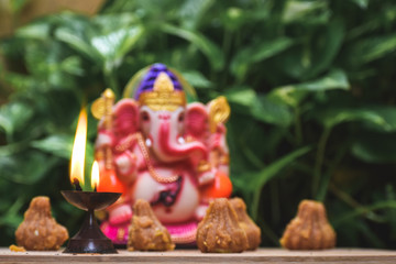 Close up shot of Diya in front of statue of lord Ganesha during the Ganesh Chaturthi festival.