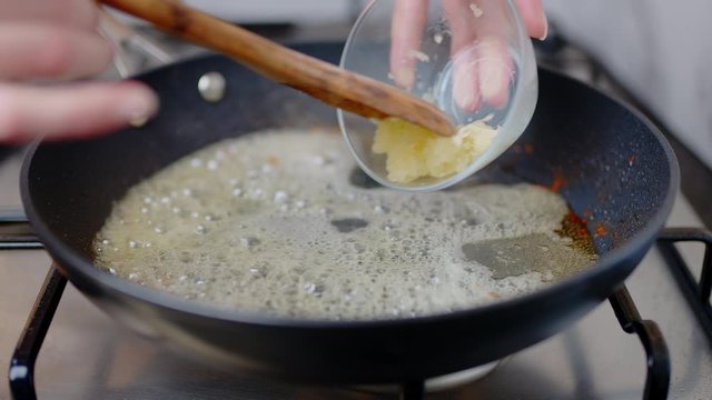 Adding chopped garlic into a preheated pan, and frying with melted cream in 4K. Concept of cooking cream sauce for scallops.
