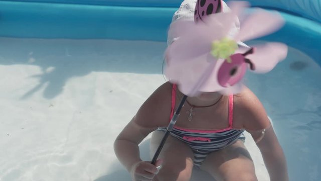 Little Happy 3 Year Old Girl In Blue Cap And Swimsuit Caucasian European Slavic Appearance Bathe And Frolic In Pool In Summer, Splashing Water, Lifestyle Design. Activity Nature Leisure. Slow Motion