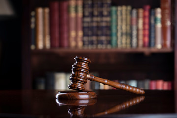 Judge‘s gavel on brown shining table and bookshelf background. Law and justice concept.