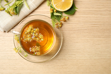 Flat lay composition with tasty tea and linden blossom on wooden table. Space for text