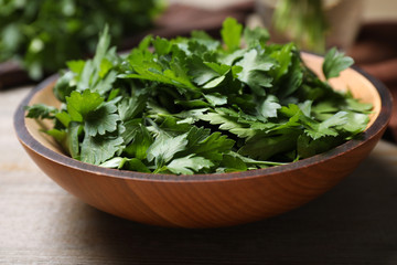 Fresh green parsley in bowl on wooden table