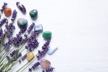 Gemstones and healing herbs on white wooden table, flat lay. Space for text