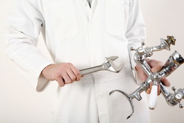 Man holding faucet and adjustable spanner in each hand