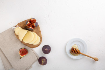 Cheese with figs and honey on white table. Cheese plate, food background. Scamorza Italian cheese. Top view, copy space.