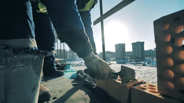 Construction worker is building a wall with bricks and cement