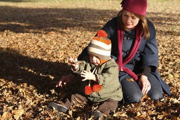 Mother watching son playing with autumn leaves