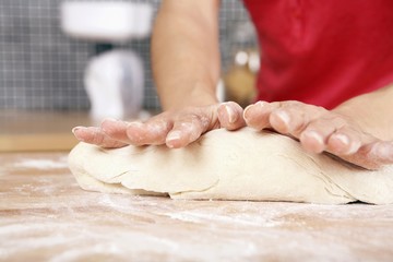 Woman kneading dough in the kitchen