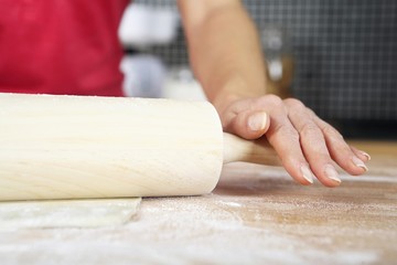 Woman kneading dough with rolling pin
