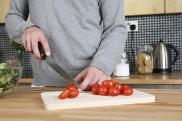 Man cutting cherry tomatoes in the kitchen