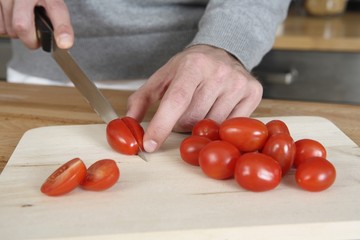Man cutting cherry tomatoes in the kitchen