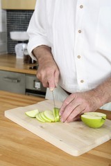 Senior man cutting apple in the kitchen