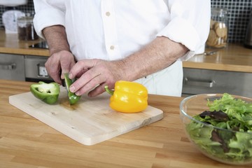 Senior man preparing salad in the kitchen