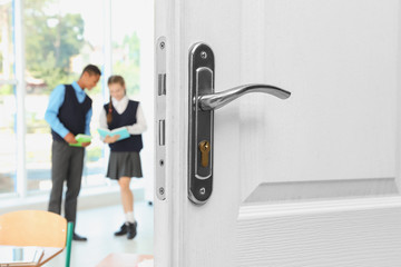 Wooden door open into modern classroom with students