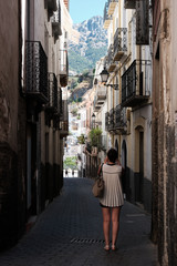 Young woman taking picture of a narrow street with the mountains in background in Cazorla, Jaén