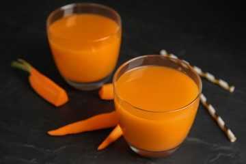 Glasses of freshly made carrot juice on black table