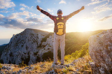 Adventurous man is on top of the mountain and enjoying the beautiful view during a vibrant sunset