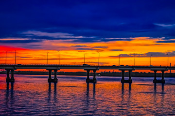 Fototapeta na wymiar Central bridge across the Dnieper river in Dnipro (Ukraine) against the background of an orange-blue sky in the evening. City landscape during sunset