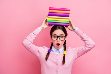 Photo of pretty student lady hold literature pile on head preparing examination college university big homework overwhelmed wear shirt pullover specs isolated pink color background