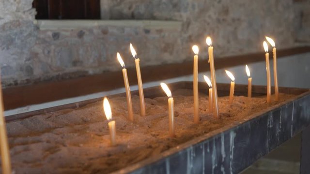 Slow-motion shooting of burning candles in the temple. 